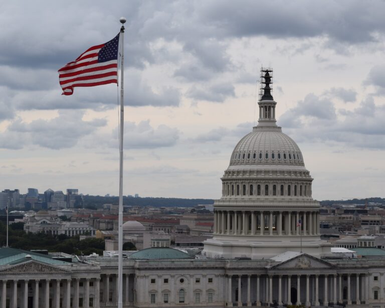 Photograph of the U.S. Capitol Building with an American Flag flying in the foreground.